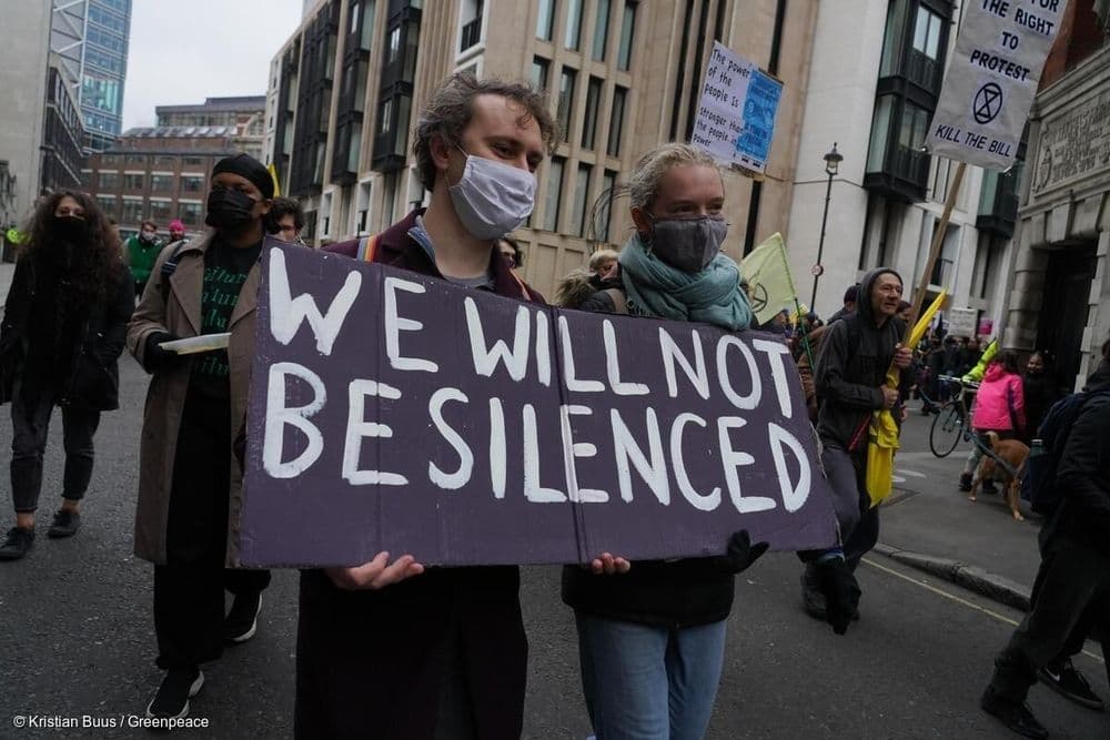 Protester marching with a billboard saying "We will not be silenced"